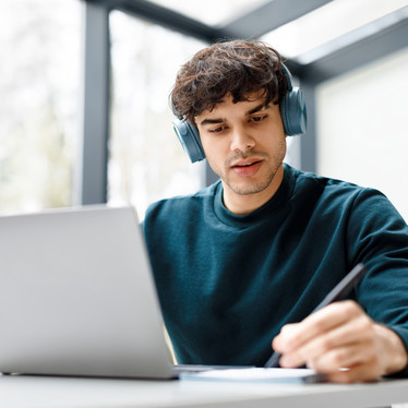 Ein junger Mann sitzt arbeitend am Laptop