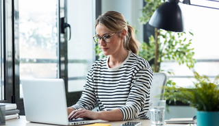 Eine Frau sitzt arbeitend an ihrem Bürotisch