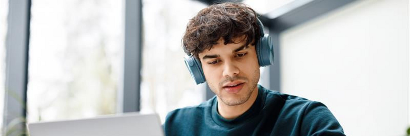 Ein junger Erwachsener sitz arbeitend am Laptop