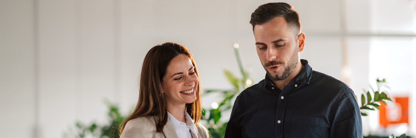 Eine Frau und ein Mann stehen nebeneinander und schauen auf ein Dokument